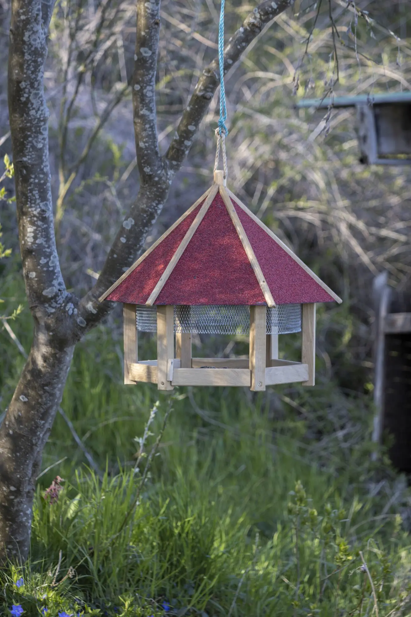 Fuglefoderhus med net. ø54 cm. Udført i FSC certificeret egetræ med tag i rødt tagpap.